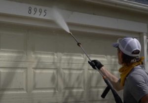 a pressure wash technician spraying the garage of a home