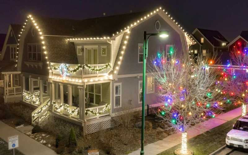 An aerial photo of a holiday light installation by kind home solutions with lights on the roofline and trees