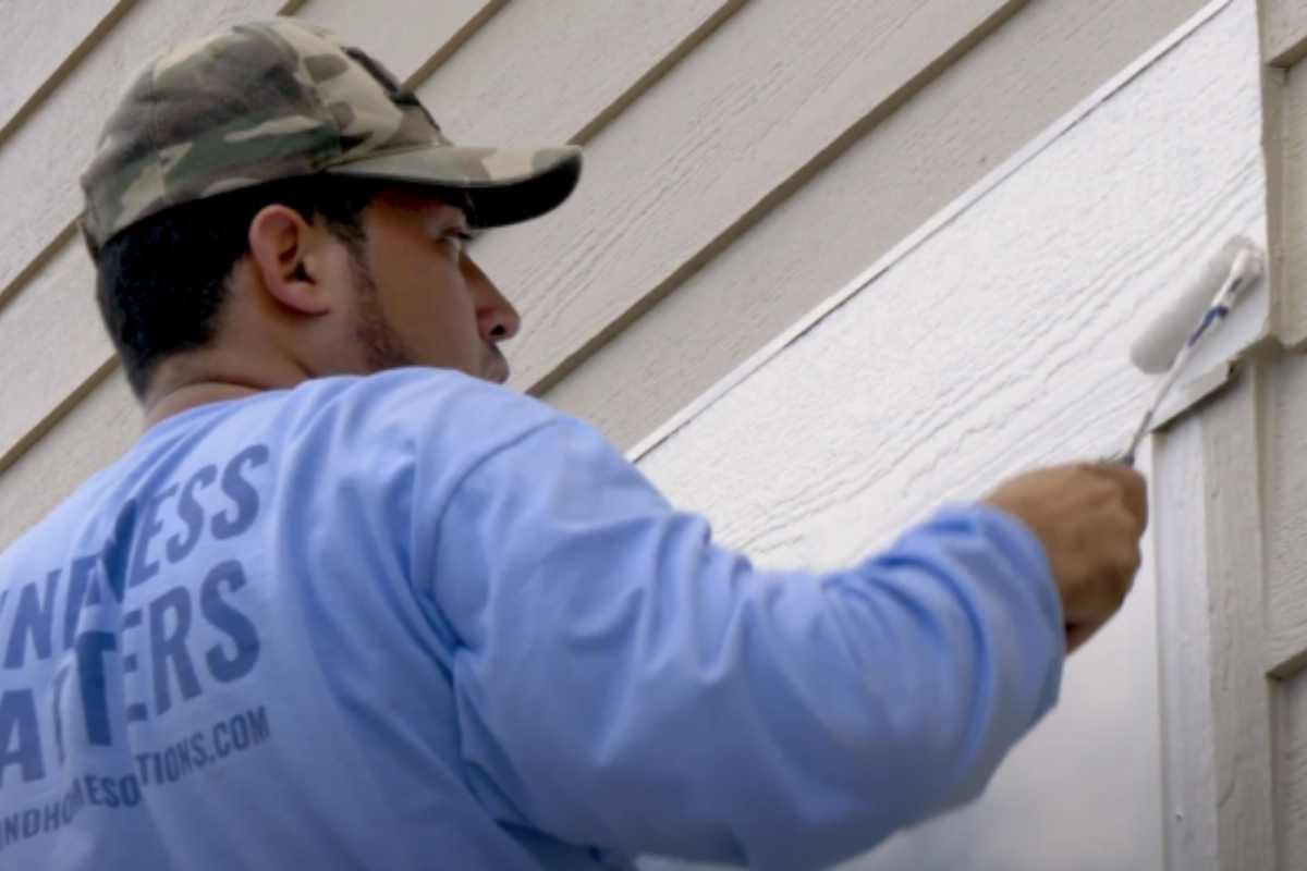 A photo of a Kind Home Solutions painter painting the trim of a home