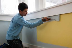 A photo of kind home solutions painter for a day painting a yellow bedroom blue