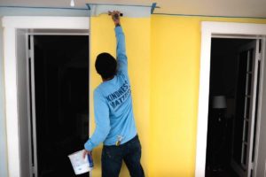 A photo of kind home solutions painter painting a yellow bedroom blue