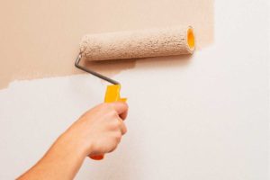 photo of a hand painting an interior with a roller