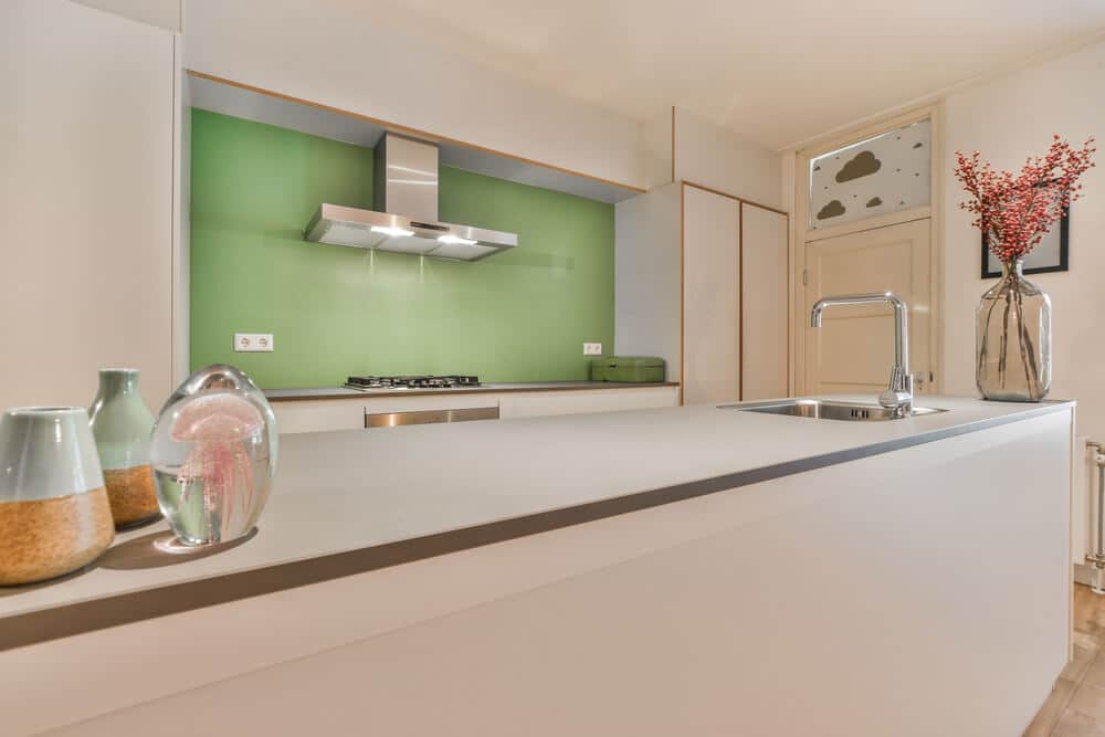 A kitchen with white counter tops and green walls -Kind Home Solutions