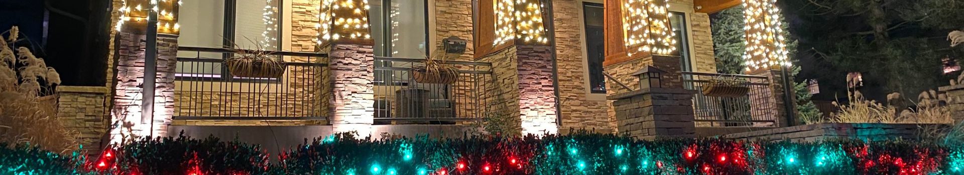 photo of house columns and bushes wrapped in holiday lights