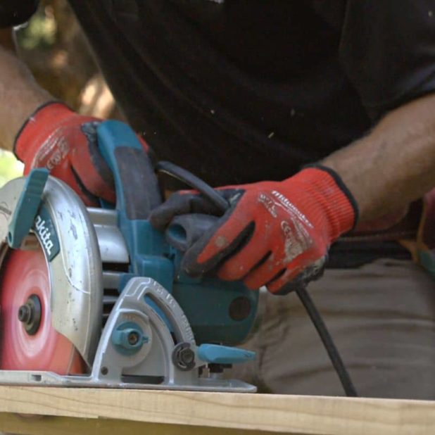 photo of a kind home employee sawing boards for wood work on a house