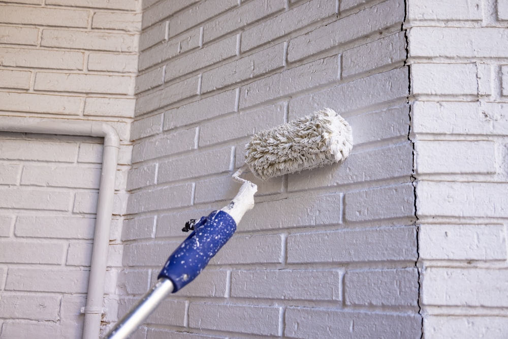 Painting a white brick wall with a wool roller